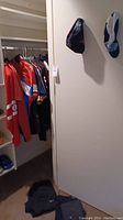 Cycling shirts hanging in a closet, multiple colors and styles mostly dark with some red and blue.