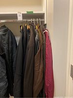 Row of hanging jackets on closet rod, seven jackets visible in various colors and materials