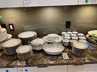 Full set on countertop showing stacks of dinner plates, salad/dessert plates, cups, saucers and serving pieces
