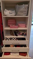 Full shelf view showing white studded bag, white laser-cut tote, pink clutches, mosaic clutch and makeup bag in drawer