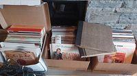 Three cardboard boxes filled with upright vinyl records