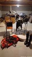 Overall view showing saddle on stand, red blanket, white pad, black boots and wooden smokers stand