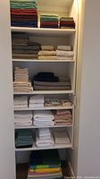 Wide view of shelving unit with multiple stacks of assorted towels by color and type