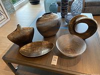 Wide view of six decorative items on table showing vase, bowls, and abstract statue.