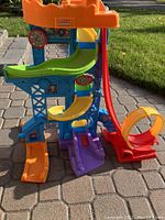 Front view of the colorful plastic play tower with multiple slides and ramps on a patio.