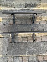 Photo showing front view of two assembled shelves with black metal brackets attached, placed on outdoor stone steps.