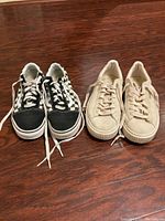 Pair of women's black and white checkered sneakers side by side with beige sneakers, showing top and front view on wood floor.