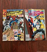 Two vintage The Amazing Spider-Man comic books side by side on a wooden floor, showing front cover art of issues featuring Spider-Man and other characters such as The Punisher and Nova.