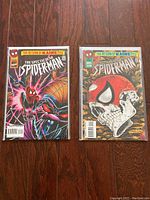 Lot of two vintage The Spectacular Spider-Man comic books in protective sleeves with backer-boards on a wooden floor.