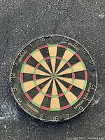 Front view of the vintage dart board showing the scoring segments in black, red, green, and beige with white numbering and branding.