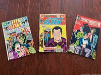 Photo of the three vintage DC comic books placed side by side on a wooden surface.