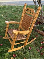 Side angle view of the vintage rocking chair showing woven seat and armrest details.