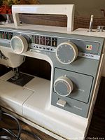 Close-up of front control panel showing stitch selector and length controls with Janome branding and carry handle on top