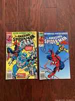 Photo showing front covers of two vintage Amazing Spider-Man comics, featuring colorful and detailed artwork with Spider-Man and robotic characters.