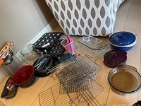 Photo showing an assortment of baking items including measuring cups, wire cooling racks, muffin pan, and glass baking pans.