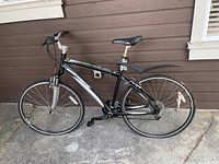 Side view of black and silver Rocky Mountain hybrid bike showing frame, tires, seat, and pedals.