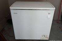 Front view of white Diplomat chest freezer showing marks and rust spots on the bottom edge with the Diplomat logo visible.