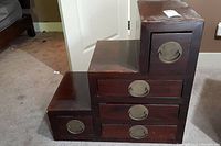 Front view of stepped chest showing drawers and brass ring pulls