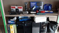 Top shelf showing two Huawei mobile WiFi boxes, 5-port Ethernet switch, two flight joysticks on silver bases, DAC interface box, computer accessory and blue tool kit case