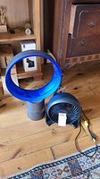 Dyson Cool fan and Honeywell fan side by side on floor showing full items.