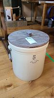 Front view of crock showing number 5 and Medalta Potteries logo, side metal handles, wooden lid on top.