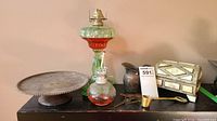 Full lot showing both glass oil lamps, metal tray, small pitcher, brass container with spoon, and decorative box.