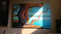 Full frontal view of large tree-and-lake oil painting hanging on wall under natural light