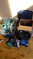 Wide view of multiple light strings in tote and box, plus parts and accessories visually shown together on floor.