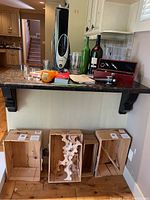 Wide view of the lot items including wine jars, bottles, cooler in box, and wooden crates on floor and counter