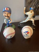 Lot contents showing signed Tom Henke bobblehead, two baseballs including one signed with multiple signatures and Toronto Blue Jays logo.