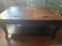 Front view of wooden coffee table showing curved legs and lower shelf