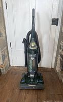 Front view of the full Dirt Devil Vision upright vacuum cleaner from top to base, showing hose and attachments stored on side.