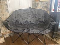 Black and grey double wide folding chair with metal frame set up, showing two-person seating area with wide fabric seat and backrest.