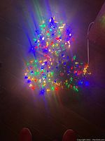 Photo showing three strands of multicolored LED Christmas lights turned on, arranged on a dark surface, displaying colorful light effects.