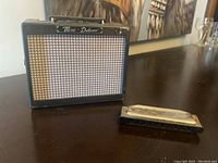 Fender Mini-Deluxe MD-20 amplifier and Hohner harmonica on dark surface, angled view