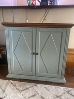 Front view of closed cabinet showing diamond panel double doors and wood top.