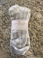 Photo of folded grey reading socks with packaging label visible reading "Chaussettes de Lecture" by Indigo