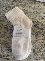 Cream colored women's reading socks with label wrapped around showing brand Indigo and product name 'Reading Socks'. The socks have a knitted pattern and ribbed cuffs.