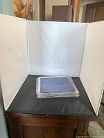 Lighting box setup with white interior diffusion panels and black base, showing size and structure suitable for small item photography.