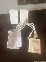 One TP-LINK WiFi range extender plugged in, with included Ethernet cable and an instruction manual placed on a table. Shows accessories included in the lot.