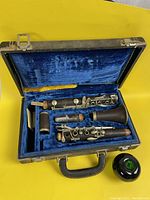 Open case showing disassembled clarinet sections, mouthpiece, ligature and brushes