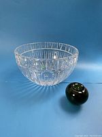Crystal bowl with geometric cut pattern and green reference apple on a blue background.
