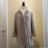 Front view of off-white sheared lamb coat on mannequin showing overall shape and length.