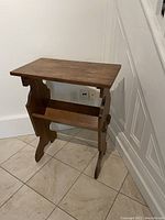 Side view of Edwardian oak side table with book rest, showing the shape of the panels and legs.