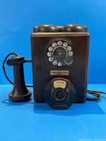 Front view of entire phone showing wood case, dual bells, rotary dial, nameplate and handset attachment