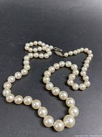 Full view of graduated pearl strand laid on black background