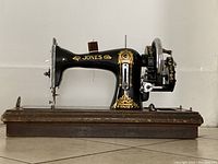 Side view of sewing machine on wooden base showing body, decals, and hand crank