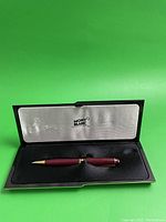 Open presentation case showing burgundy pen on grey satin interior