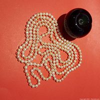 Overall view of full pearl strand next to a 3-inch reference apple