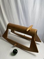 Front-side angle view of the wooden rocking toy with a small green apple placed for size reference.